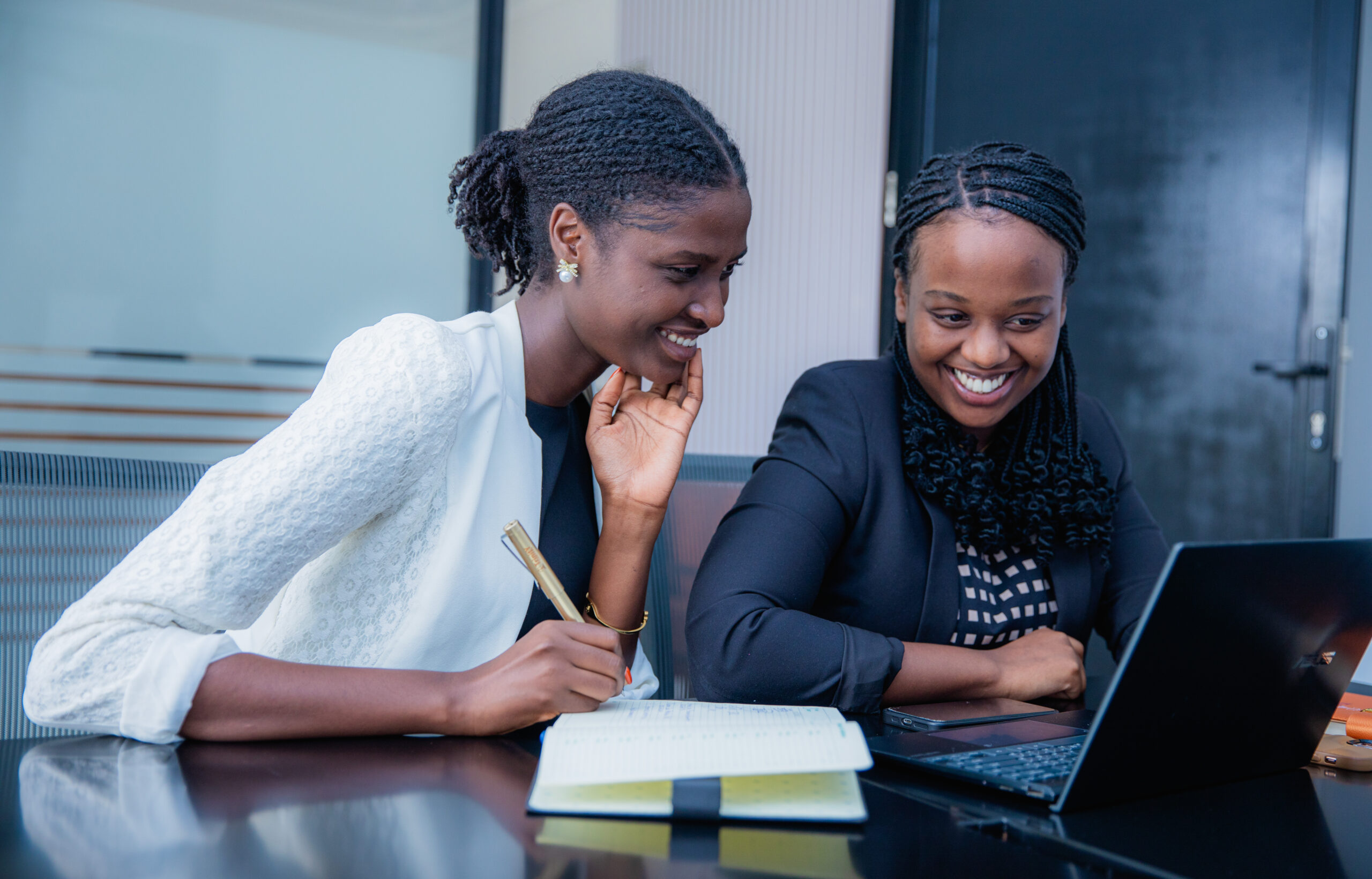 Two colleagues smiling over a laptop